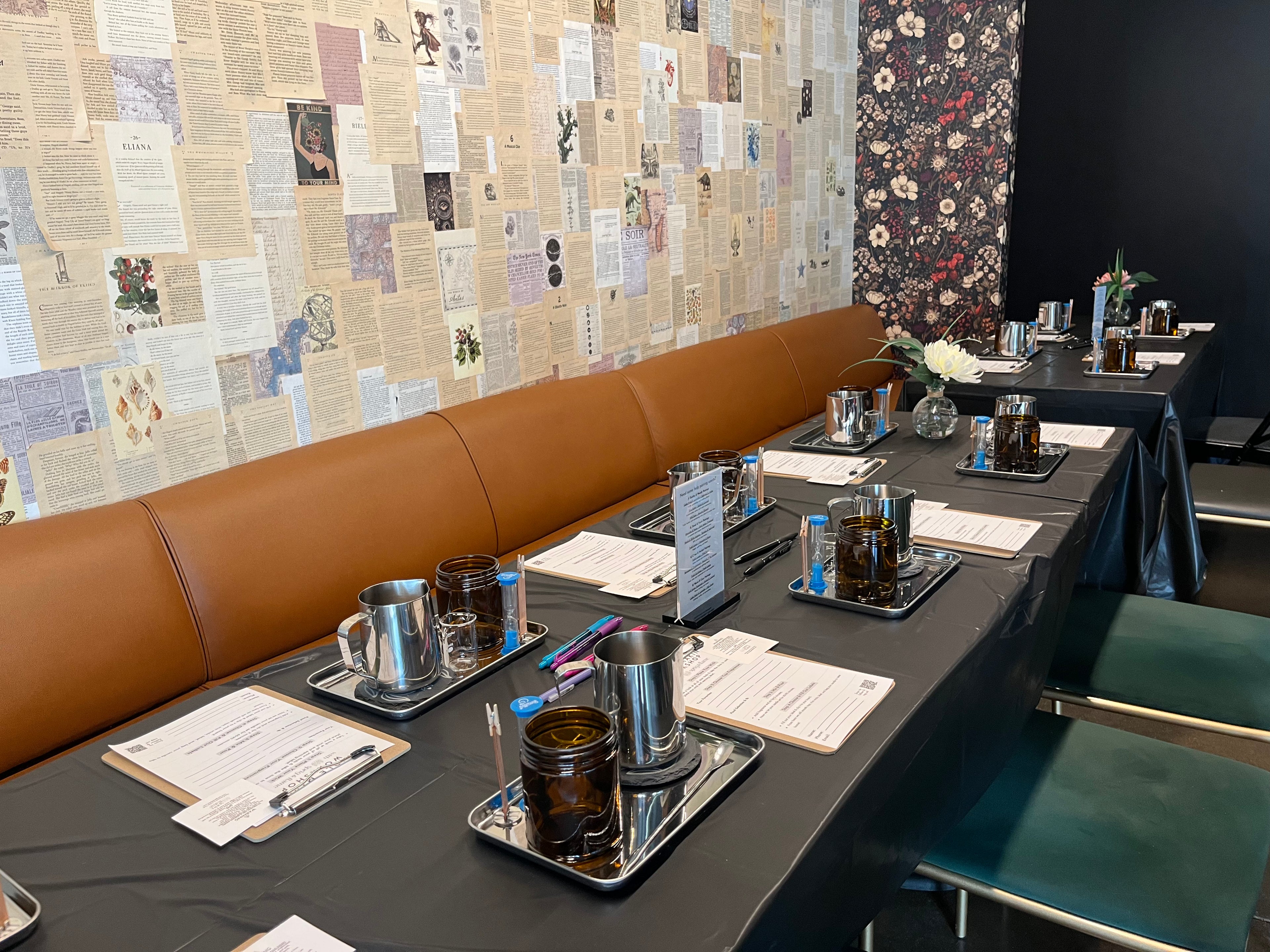 Dining area converted to worktables featuring brown leather booths and a decorative wall. Each place setting is set up for candle making with all the supplies and tools.
